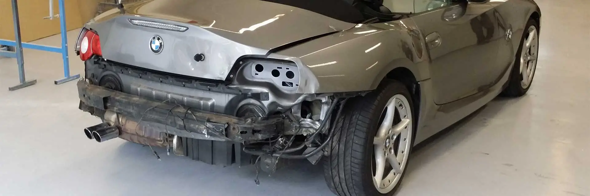 Grijze BMW Z4 met schade aan de achterbumper in de werkplaats