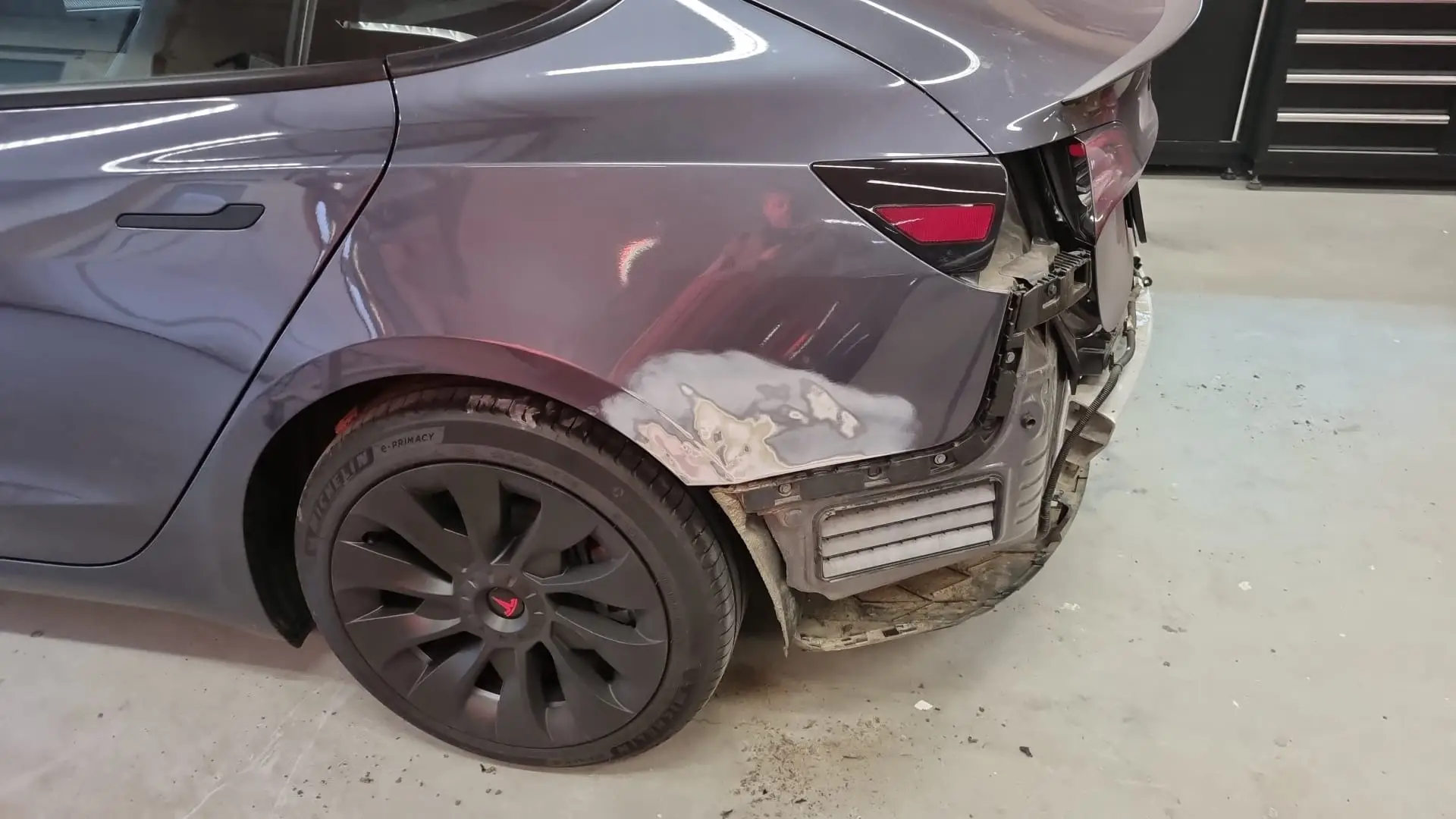 Achterscherm van een Tesla Model 3 in reparatie, geplamuurd voor het spuiten