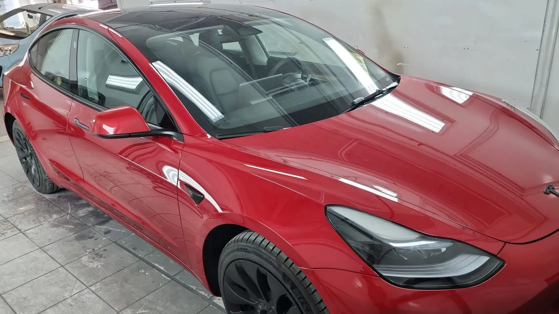 Rode Tesla Model 3 glanzend afgewerkt na schadeherstel in de spuitcabine