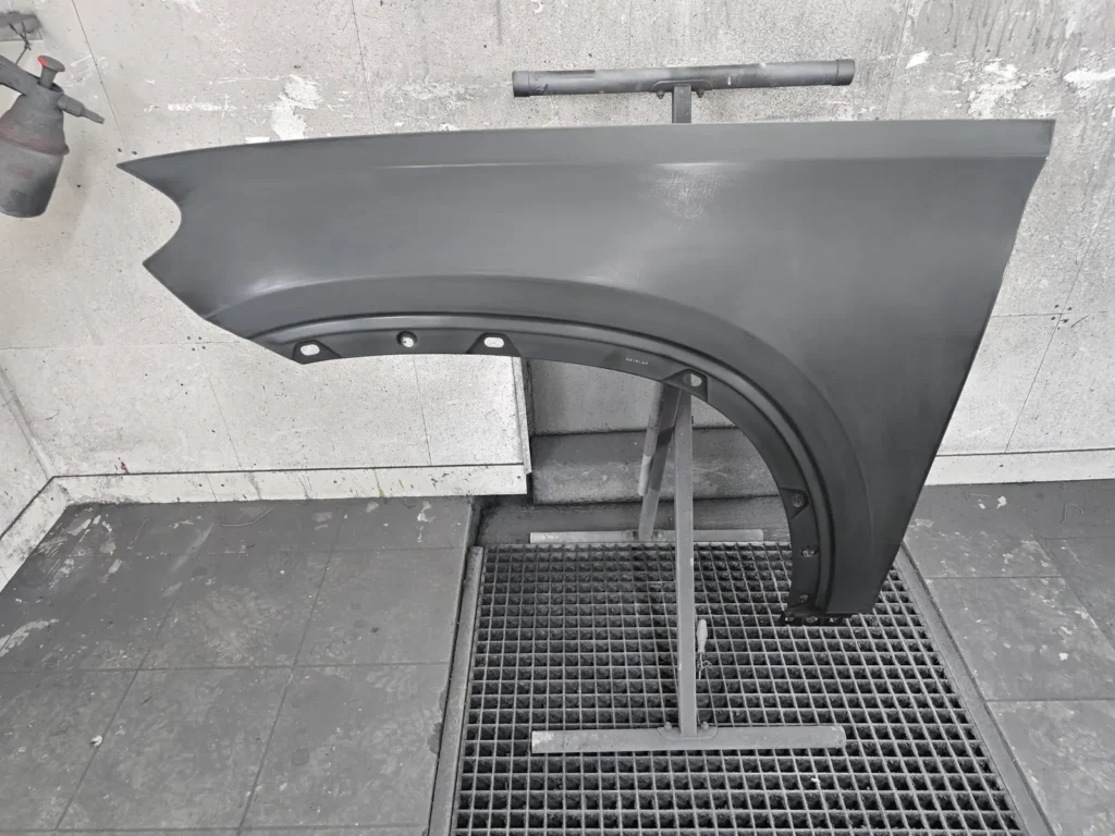 Nieuw voorscherm in grijze grondlaag op een spuitstandaard, voorbereid voor de kleurlaag